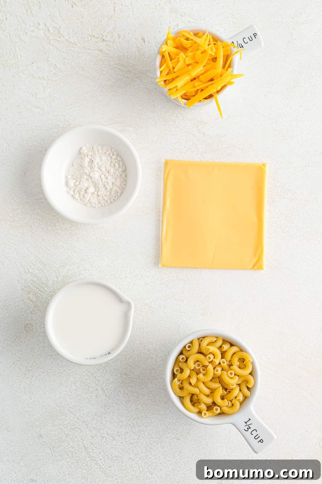 Ingredients needed for the microwave mac and cheese recipe, including cheese, macaroni pasta, milk, and flour.