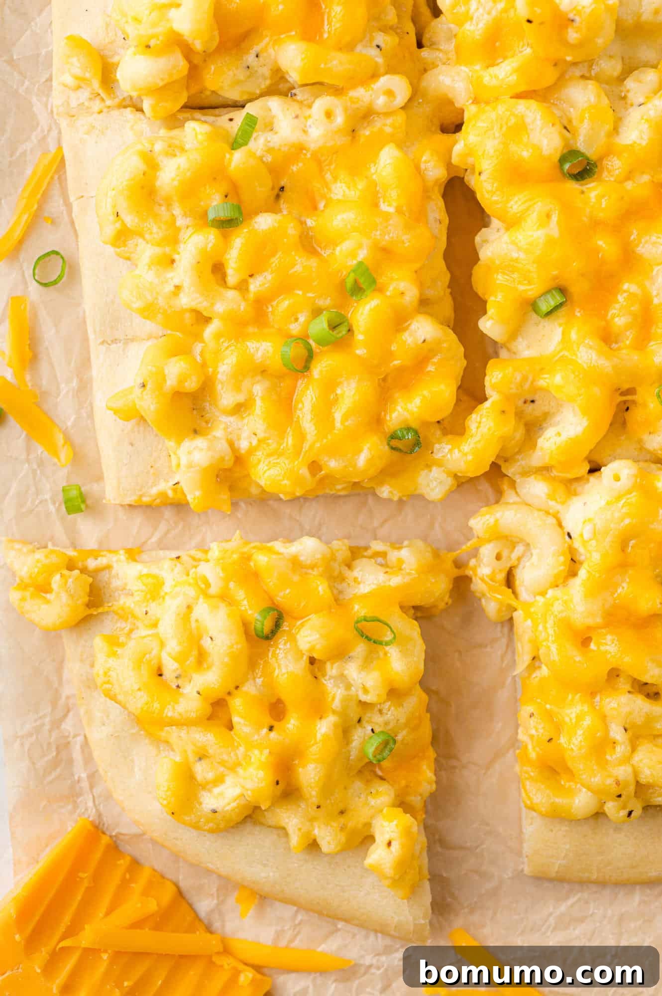 Ultimate Comfort Pizza 2 Golden-brown mac and cheese pizza, generously topped with fresh green onions and neatly cut into squares, ready to serve.