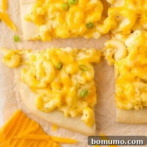 Mac and cheese pizza cut into squares, ready to be served.