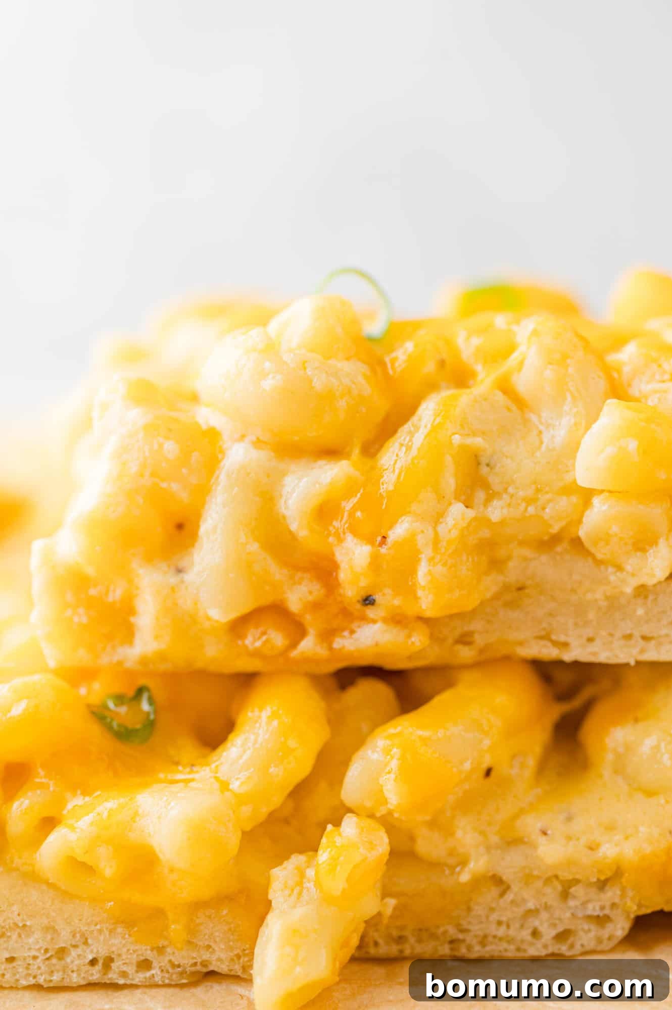 Ultimate Comfort Pizza 3 Several thick slices of mac and cheese pizza, layered on top of each other, showcasing the rich macaroni and cheese topping and crispy crust.