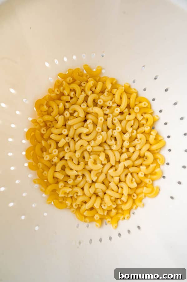 Ultimate Comfort Pizza 5 Cooked elbow macaroni pasta resting in a colander after being drained.