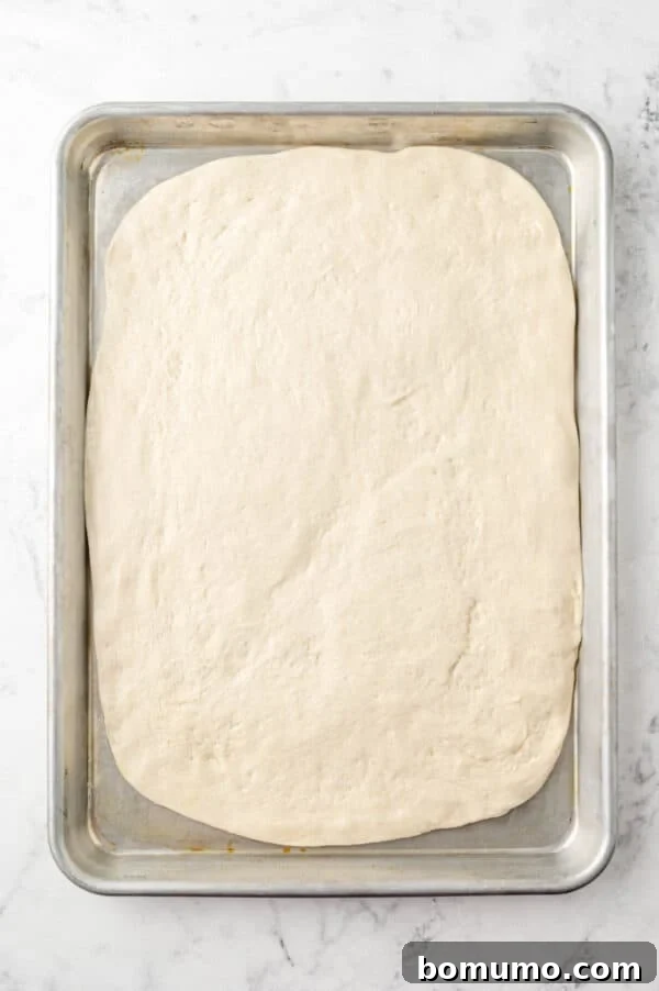 Ultimate Comfort Pizza 9 Fresh pizza dough carefully spread into a sheet pan, lightly coated with olive oil and ready for pre-baking.
