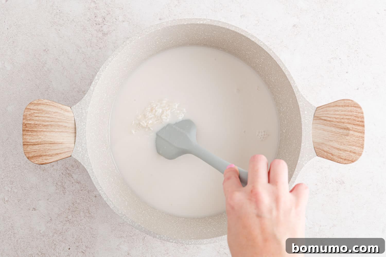 Tropical Coconut Bliss 7 Uncooked jasmine rice, coconut milk, and water being stirred together in a saucepan.