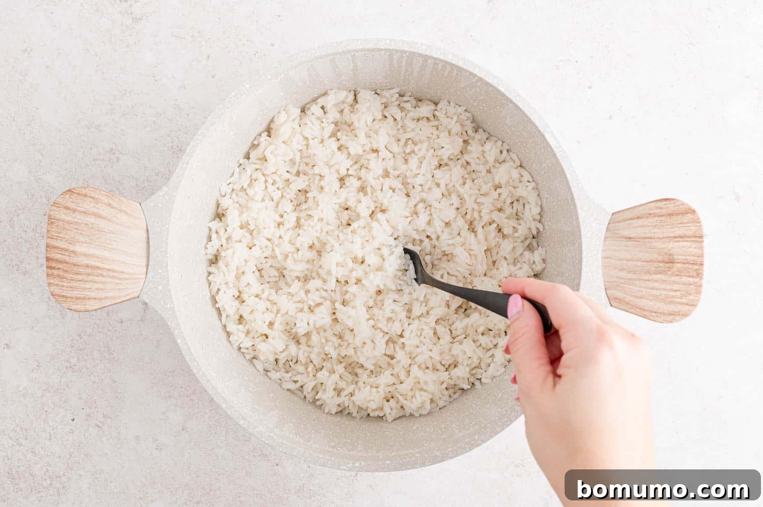 Tropical Coconut Bliss 9 Cooked coconut rice being fluffed with a fork in a saucepan, revealing perfectly separated grains.