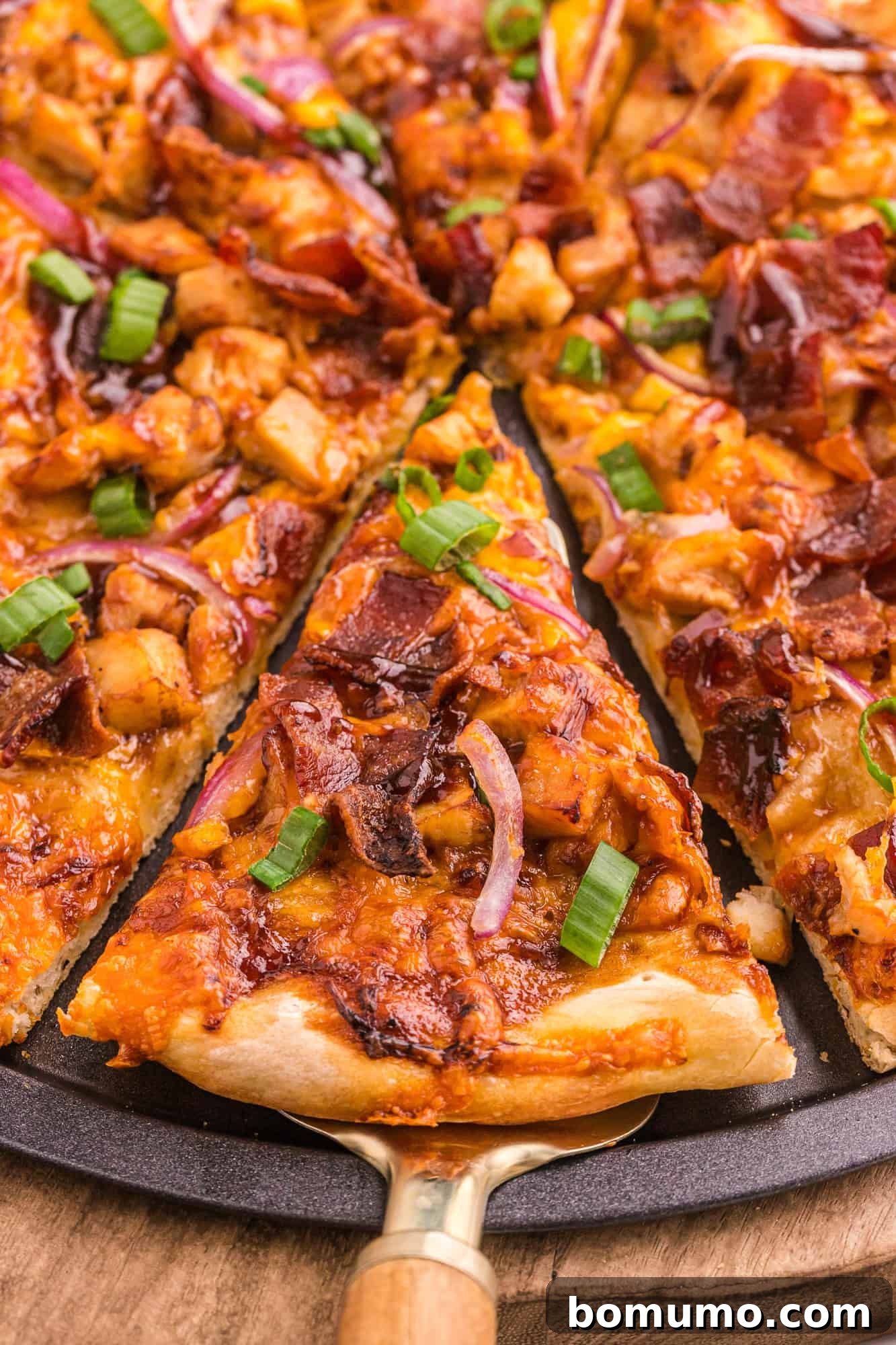 A mouth-watering slice of BBQ chicken pizza, hot and fresh, being carefully lifted from the pan, showcasing its crispy crust, melted cheese, and abundant toppings.