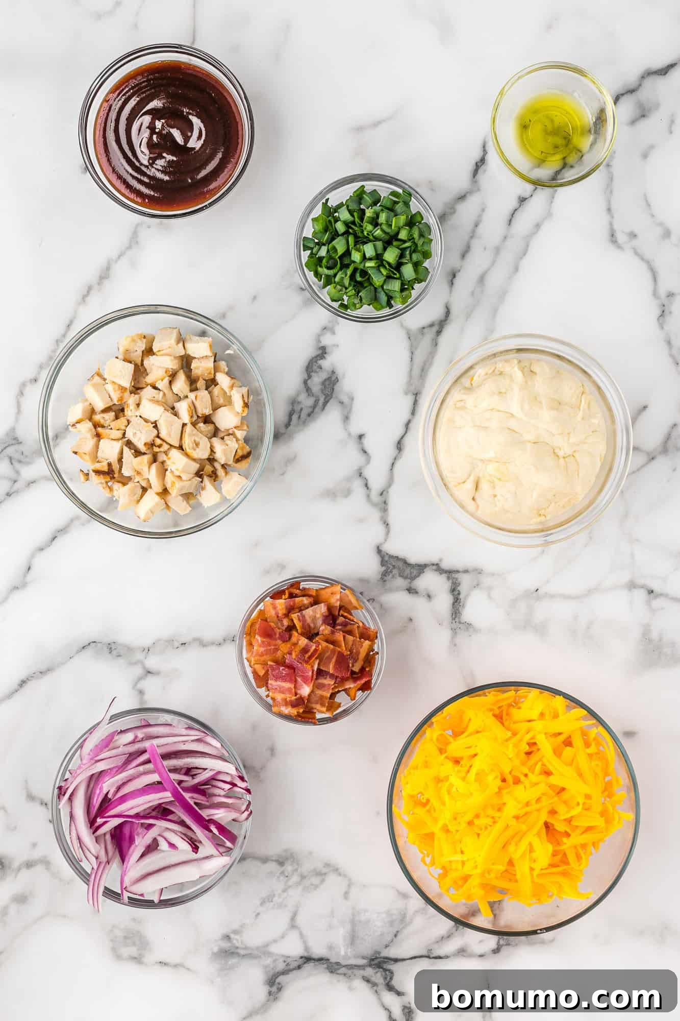 An overhead view capturing all the fresh and vibrant ingredients neatly arranged, ready to be transformed into a delicious homemade BBQ chicken pizza.