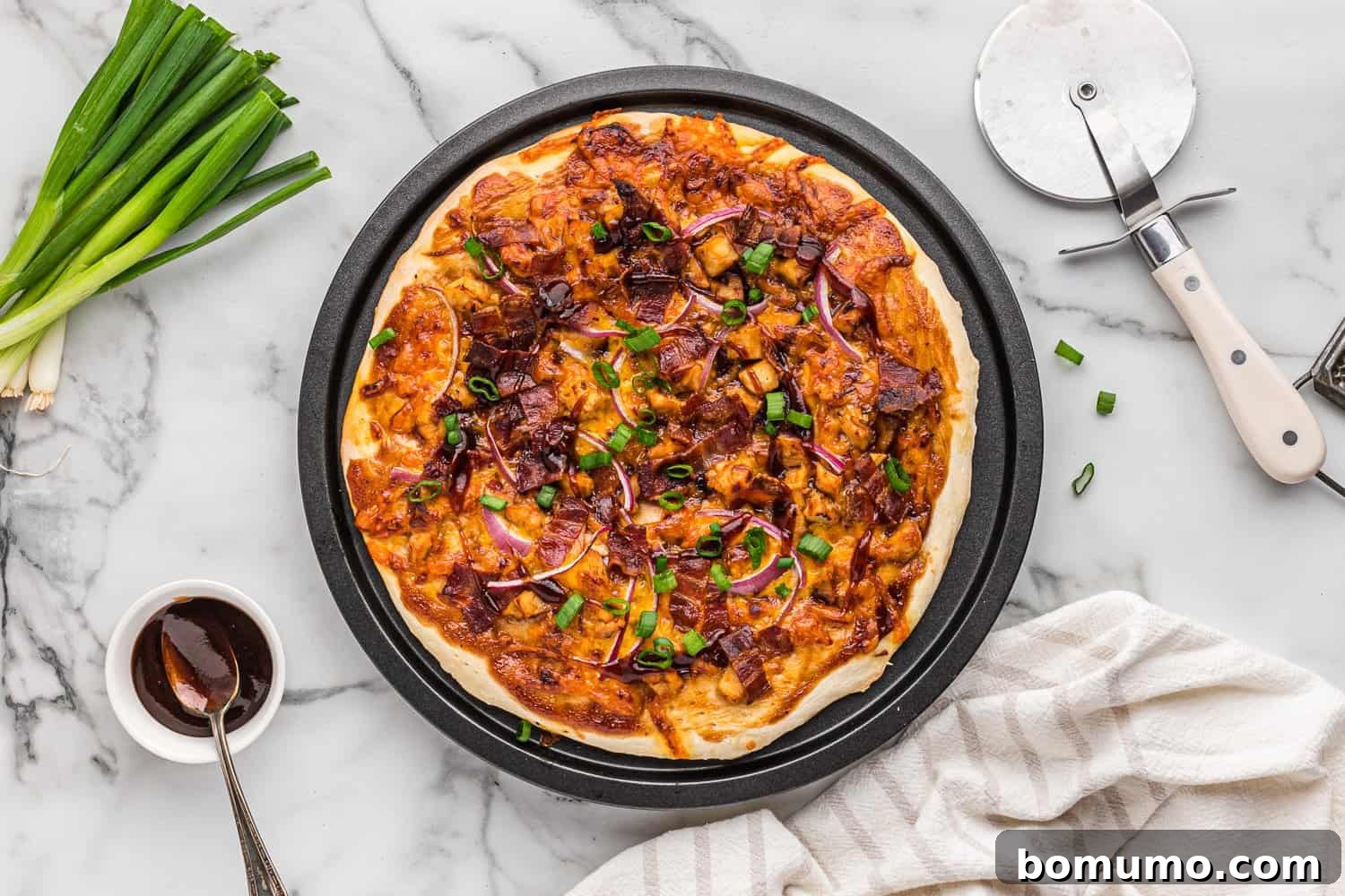 A freshly baked BBQ chicken pizza, adorned with vibrant green onions, glistening with melted cheese and ready to be served.