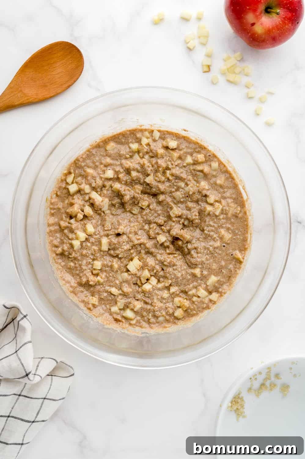 The completed apple quinoa pancake batter in a clear glass mixing bowl, showcasing its rich texture.