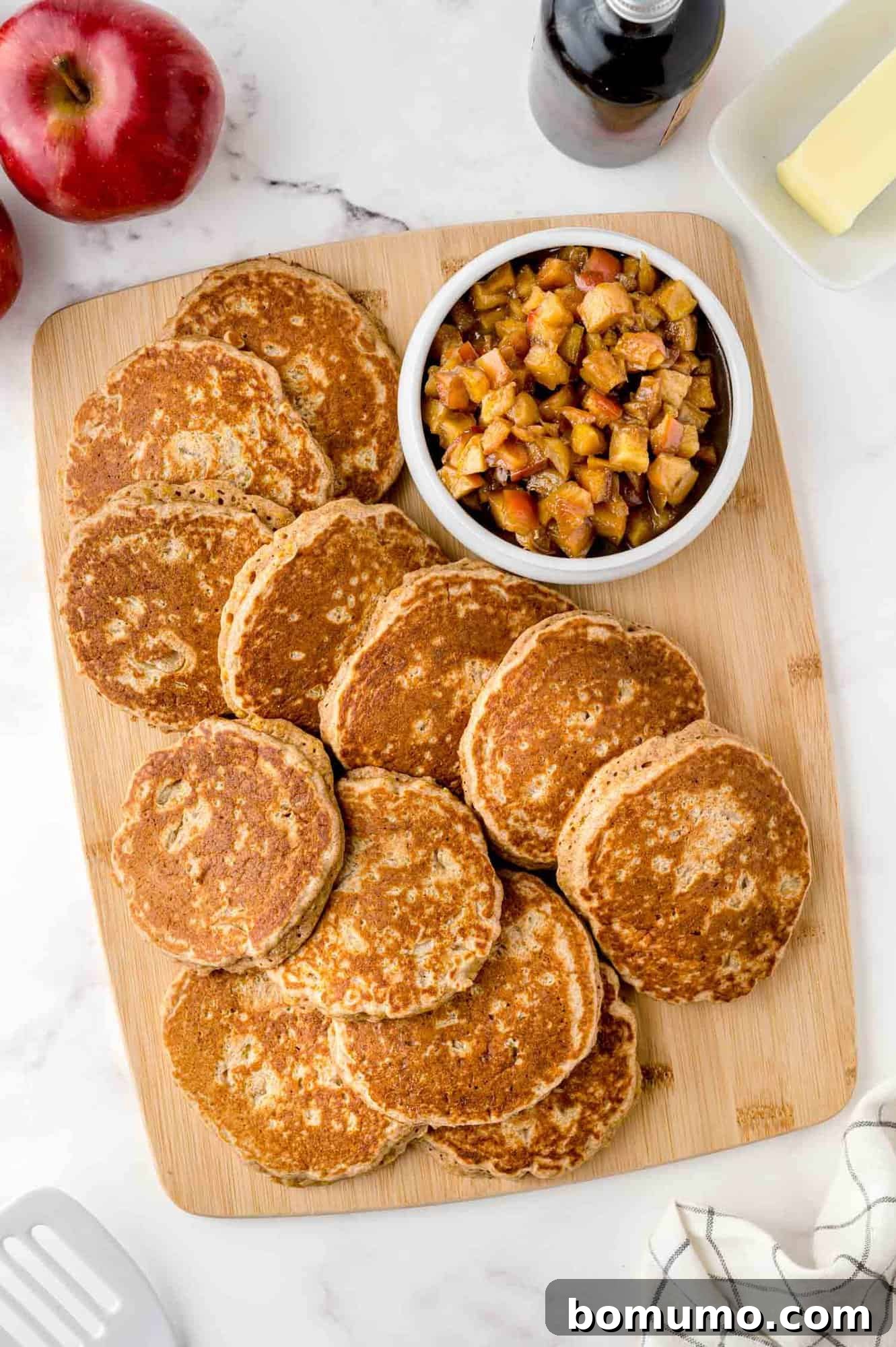 Stack of apple quinoa pancakes on a wooden cutting board.