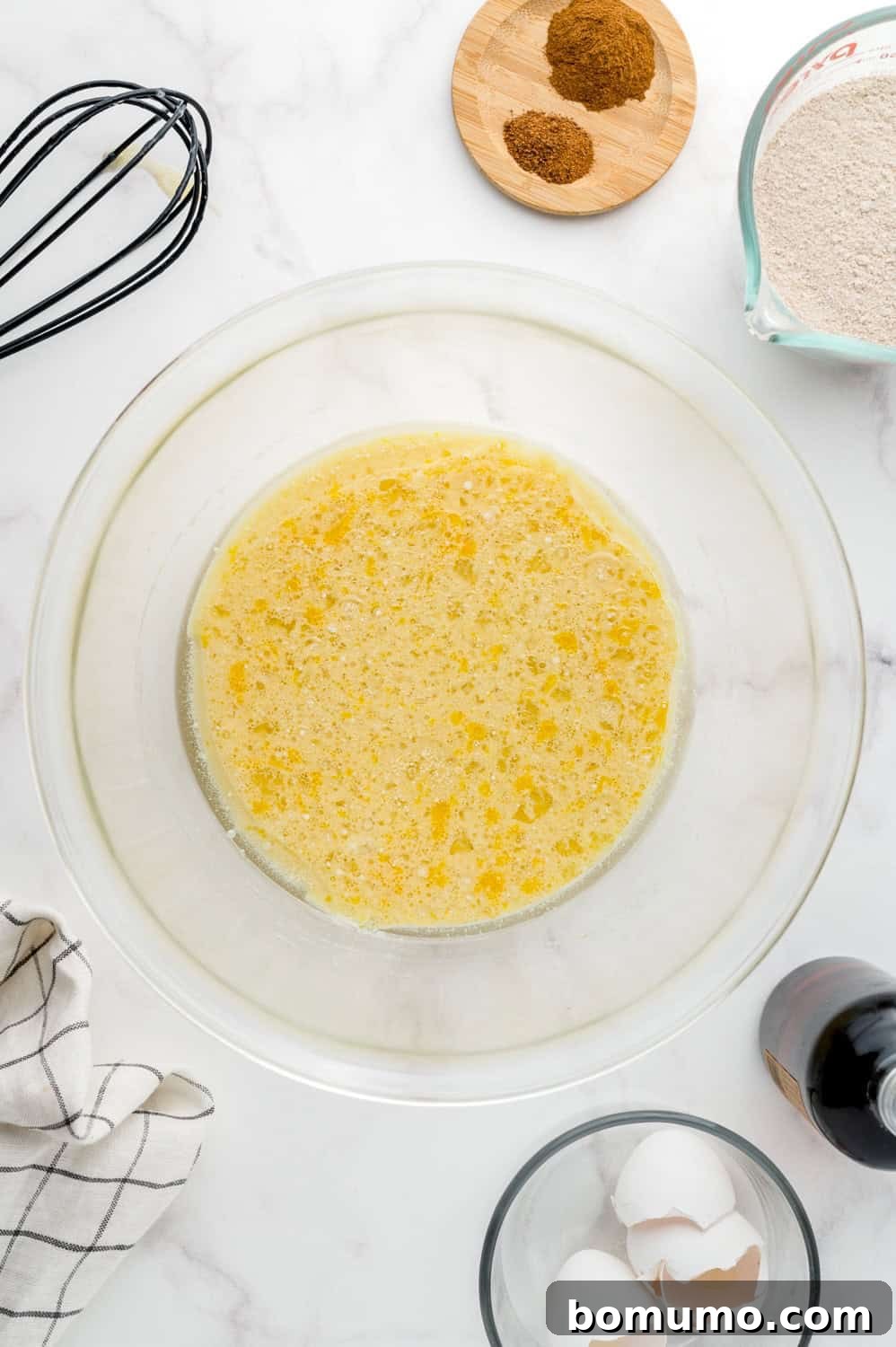 Wet ingredients perfectly mixed in a clear glass mixing bowl, ready for dry additions.