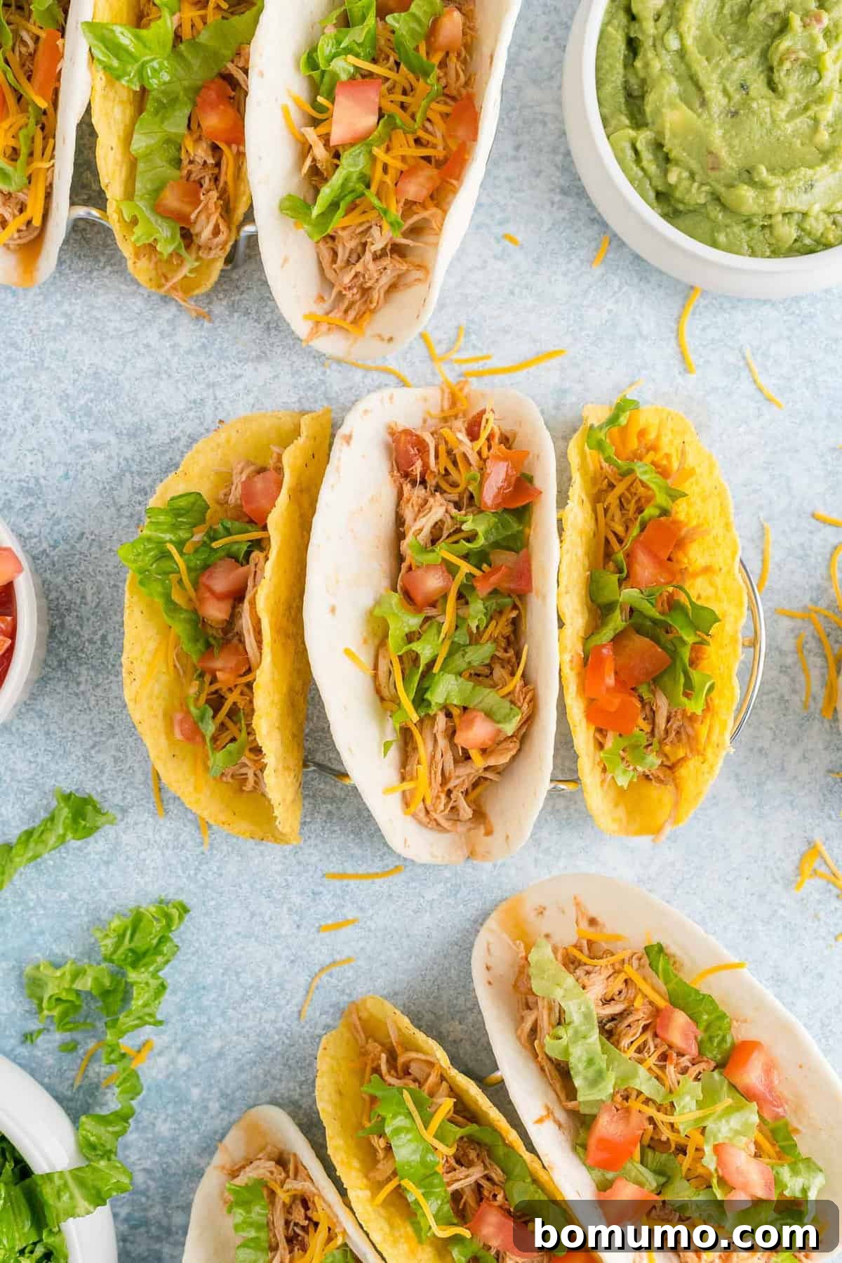 Multiple tacos filled with chicken, tomatoes, and lettuce.