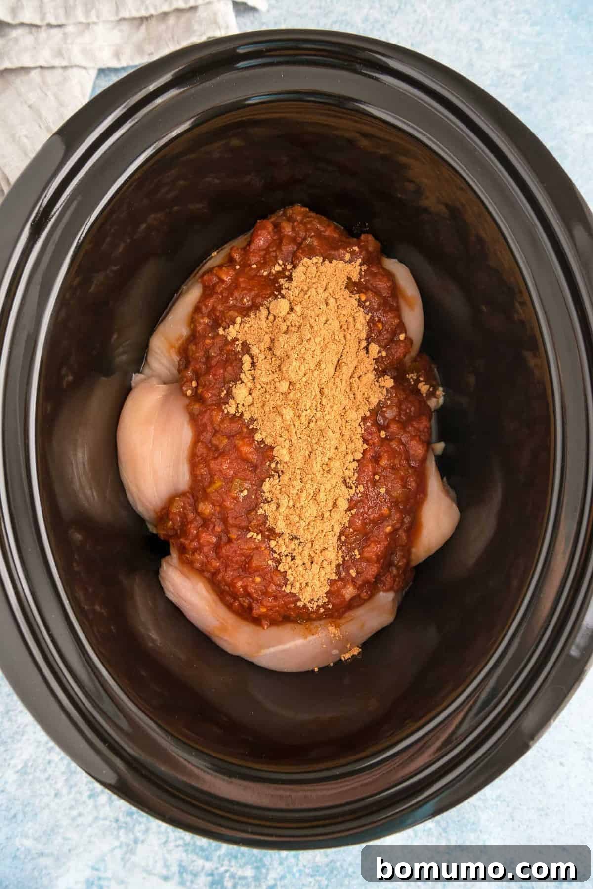 Chicken, salsa, and taco seasoning in a slow cooker.