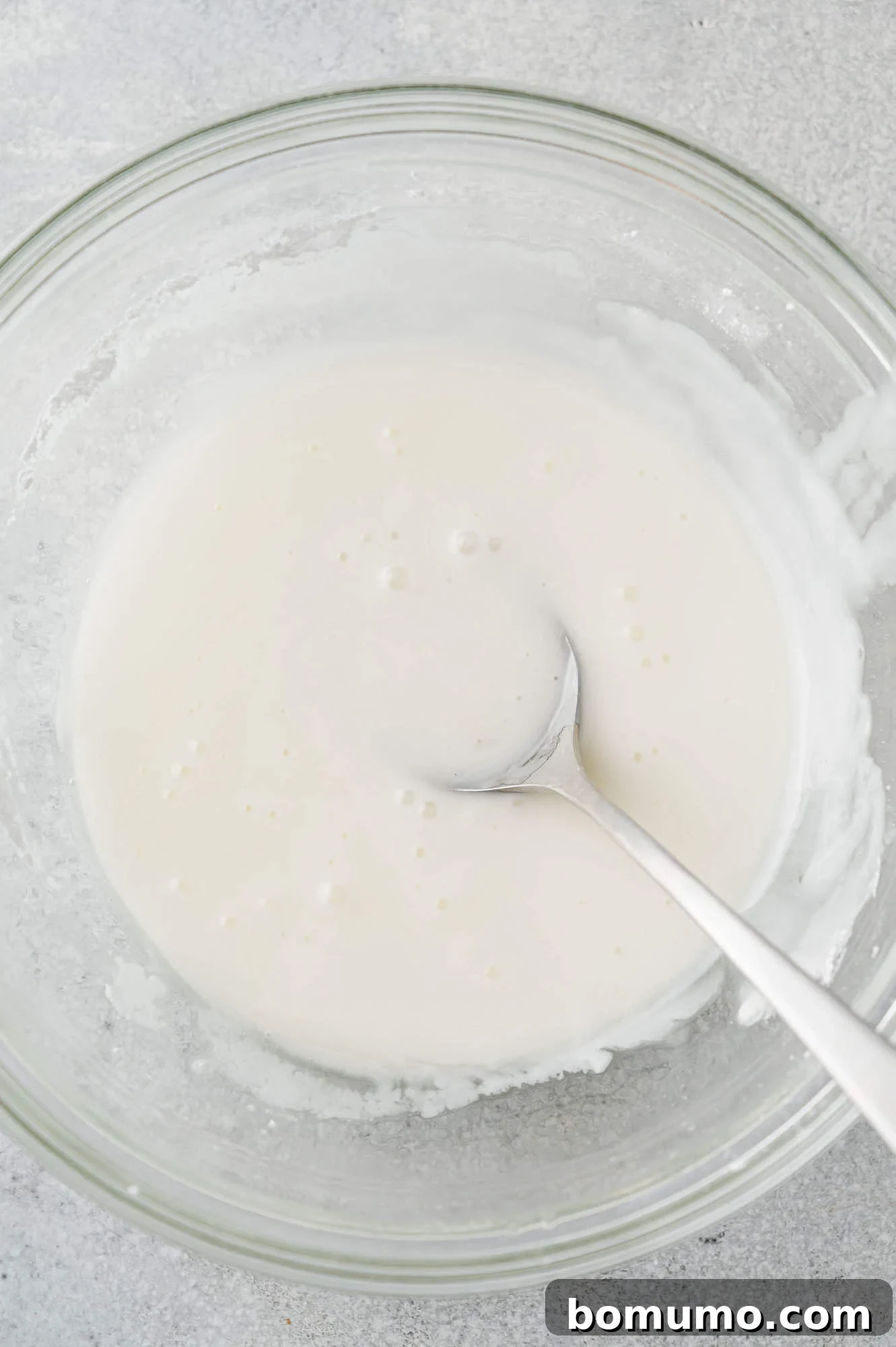 A bowl of freshly mixed lemon glaze, smooth and ready to be drizzled, highlighted against a soft background.