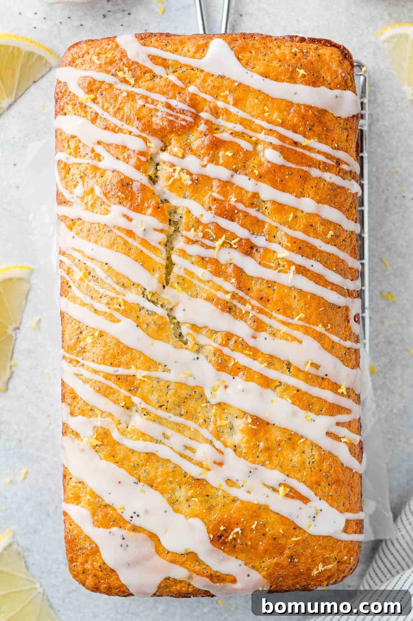 Glistening lemon glaze being artistically drizzled over the top of a golden-brown lemon poppy seed bread loaf, creating an inviting finish.