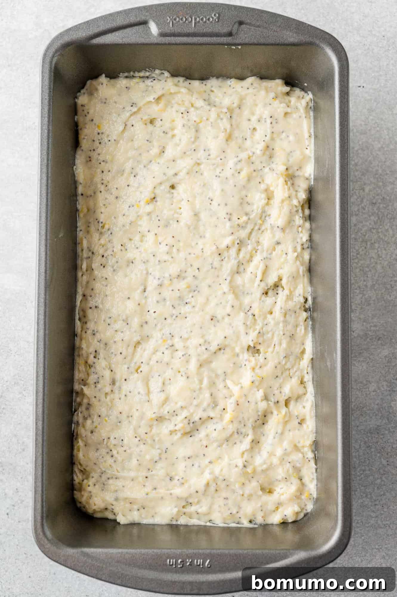 The prepared lemon poppy seed bread batter spread evenly into a loaf pan, ready for baking.