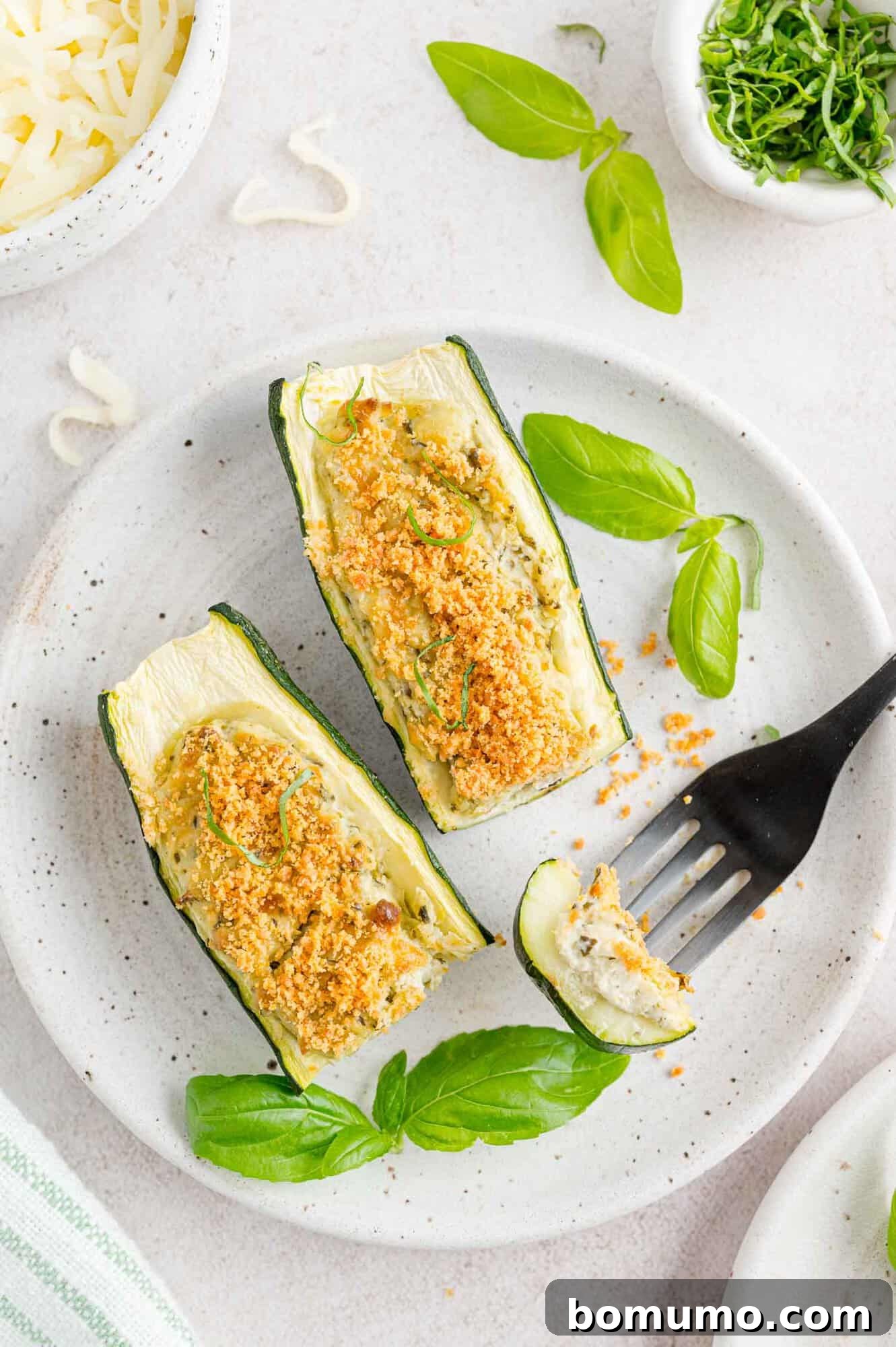 Cheese and pesto stuffed zucchini, halved and baked to perfection, revealing a vibrant green and white filling.
