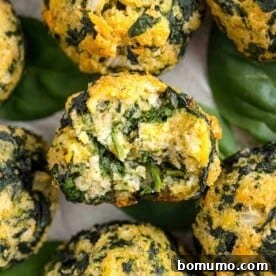 Perfectly baked spinach balls, one with a small bite taken out, invitingly arranged on a platter for an appetizer.
