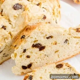 A beautifully sliced loaf of traditional Irish soda bread, revealing its soft, rustic interior dotted with sweet raisins, ready to be enjoyed.