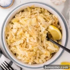 A bowl filled with perfectly sautéed cabbage, glistening with butter, with a serving spoon resting inside, ready to be enjoyed as a side dish.
