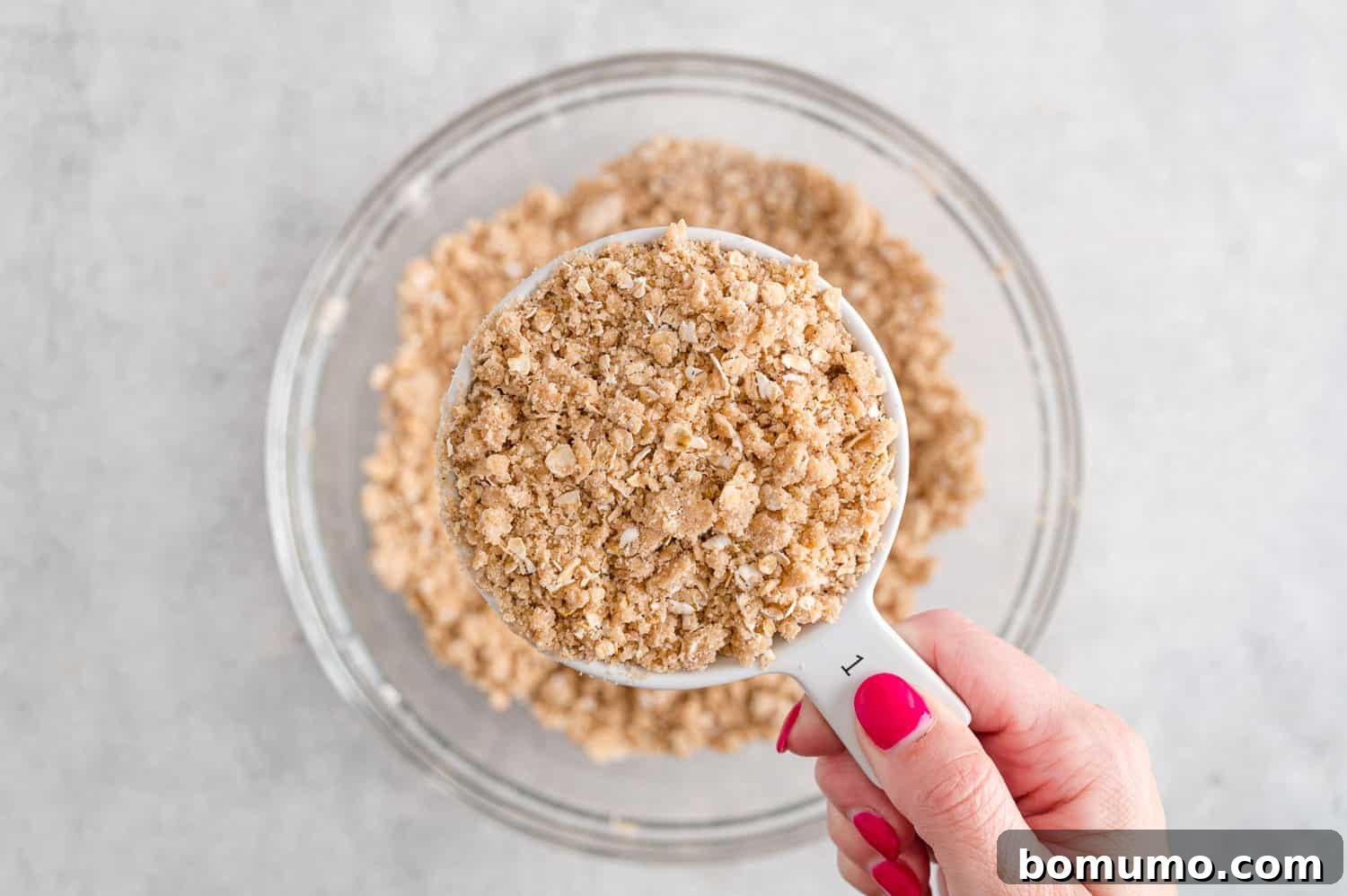 A portion of the crumbly mixture measured out in a measuring cup.
