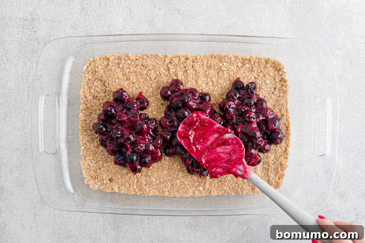 The blueberry filling being carefully spread over the warm, par-baked crust.