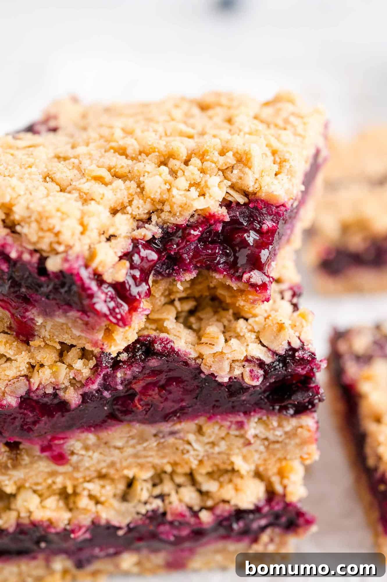 A blueberry crumb bar with a bite taken out, revealing the vibrant filling and crumbly texture.