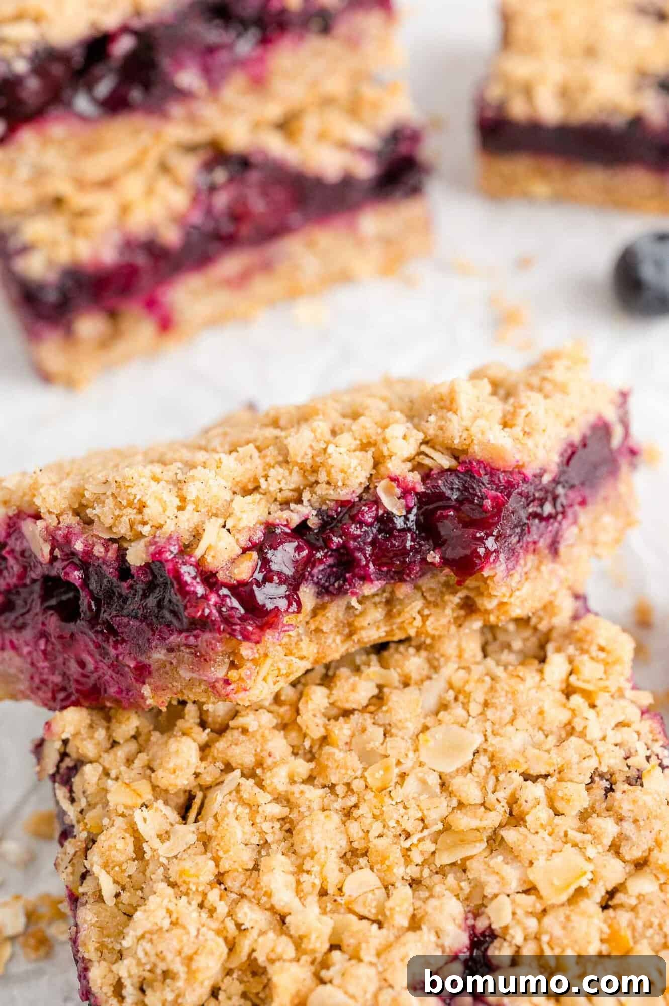 A close-up view of a blueberry crumb bar with a section bitten off, highlighting the texture and filling.