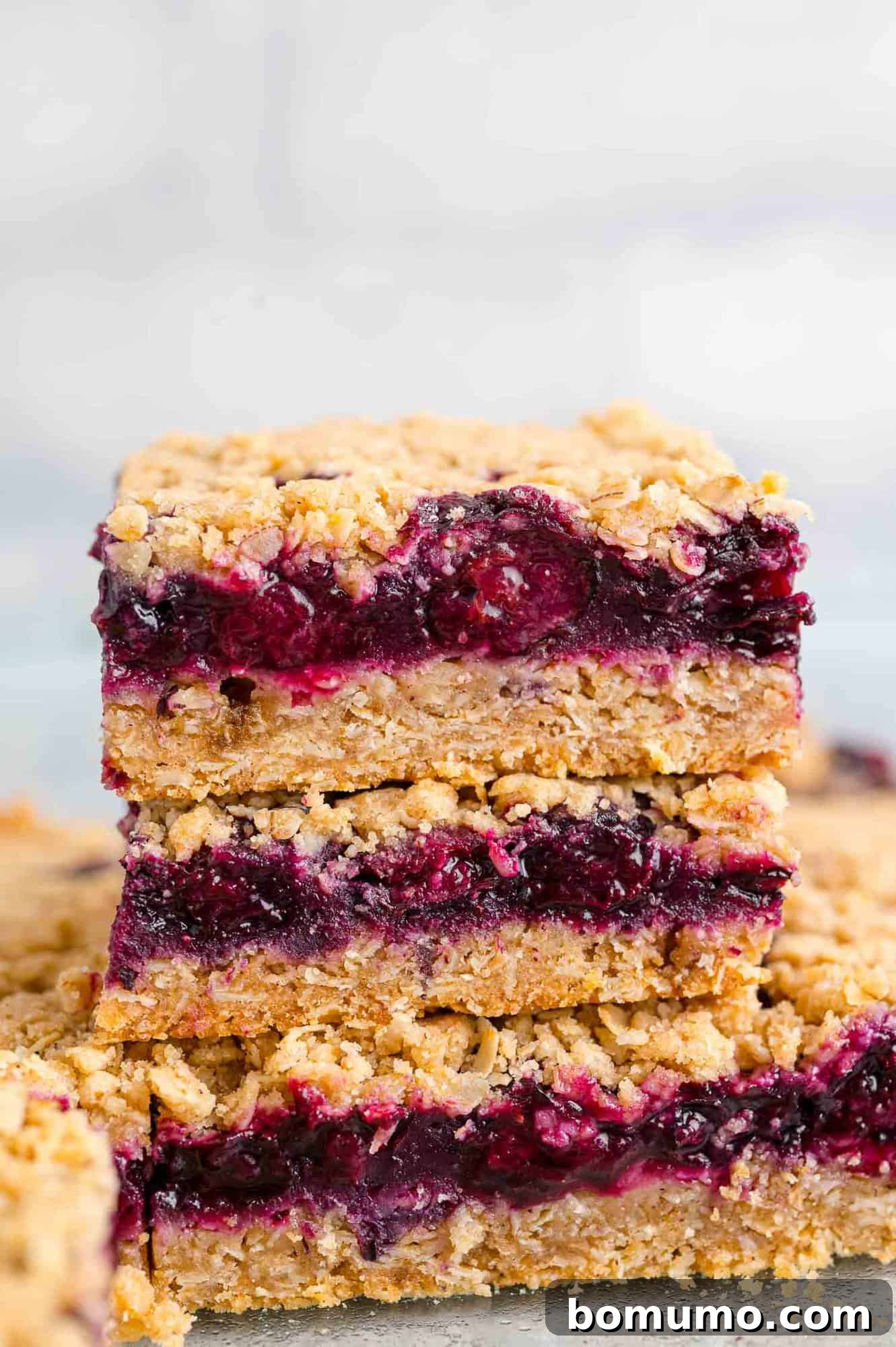 Three perfectly stacked blueberry crumb bars, showcasing their distinct layers.