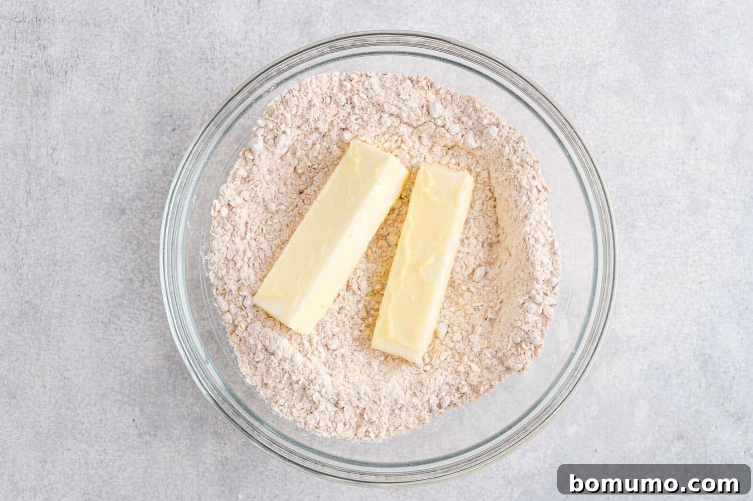 Softened butter being added to the dry oat and flour mixture.