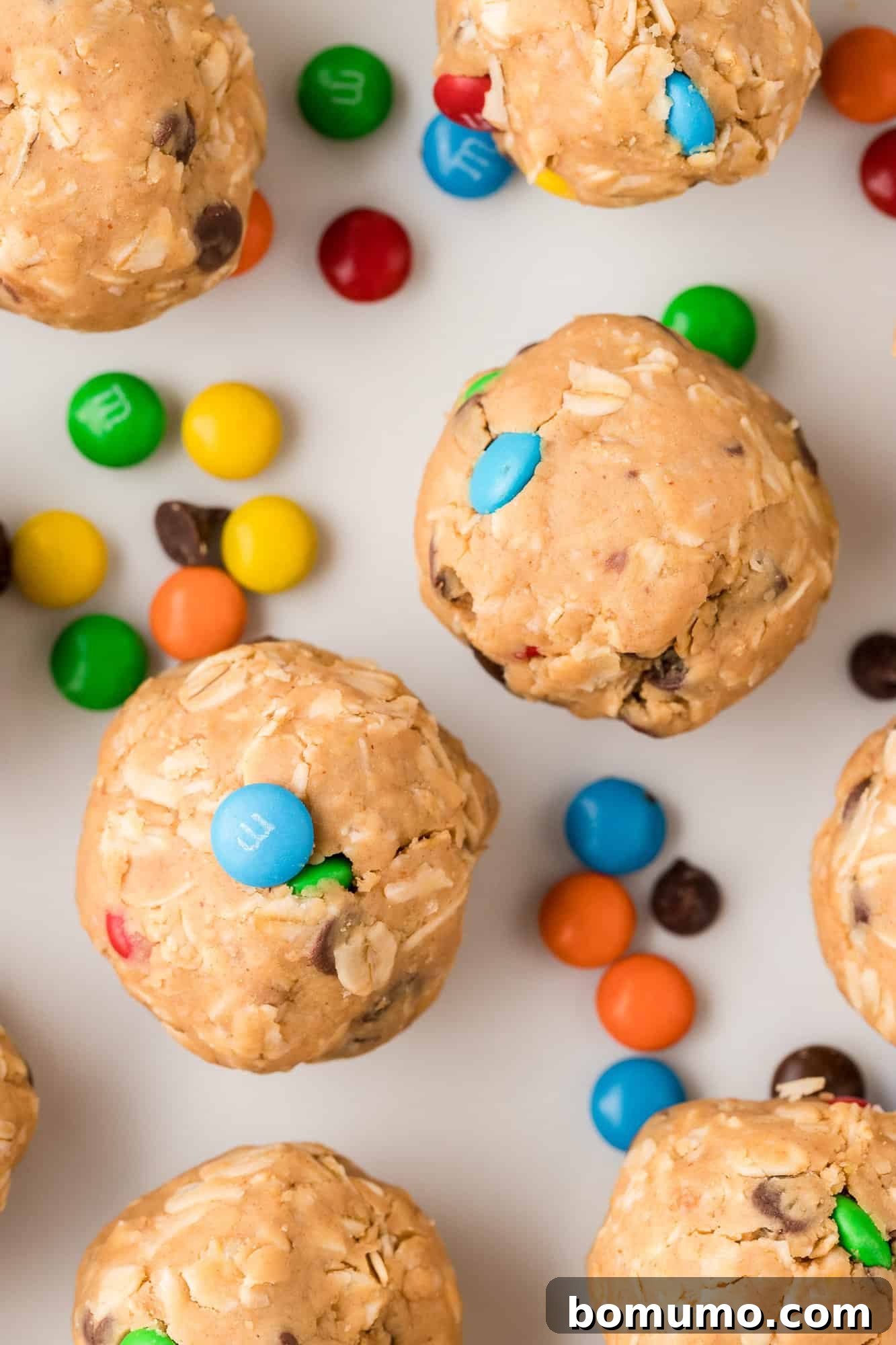 Vibrant Monster Cookie Energy Bites featuring peanut butter, oats, chocolate chips, and colorful M&M's, arranged appealingly on a clean white background.