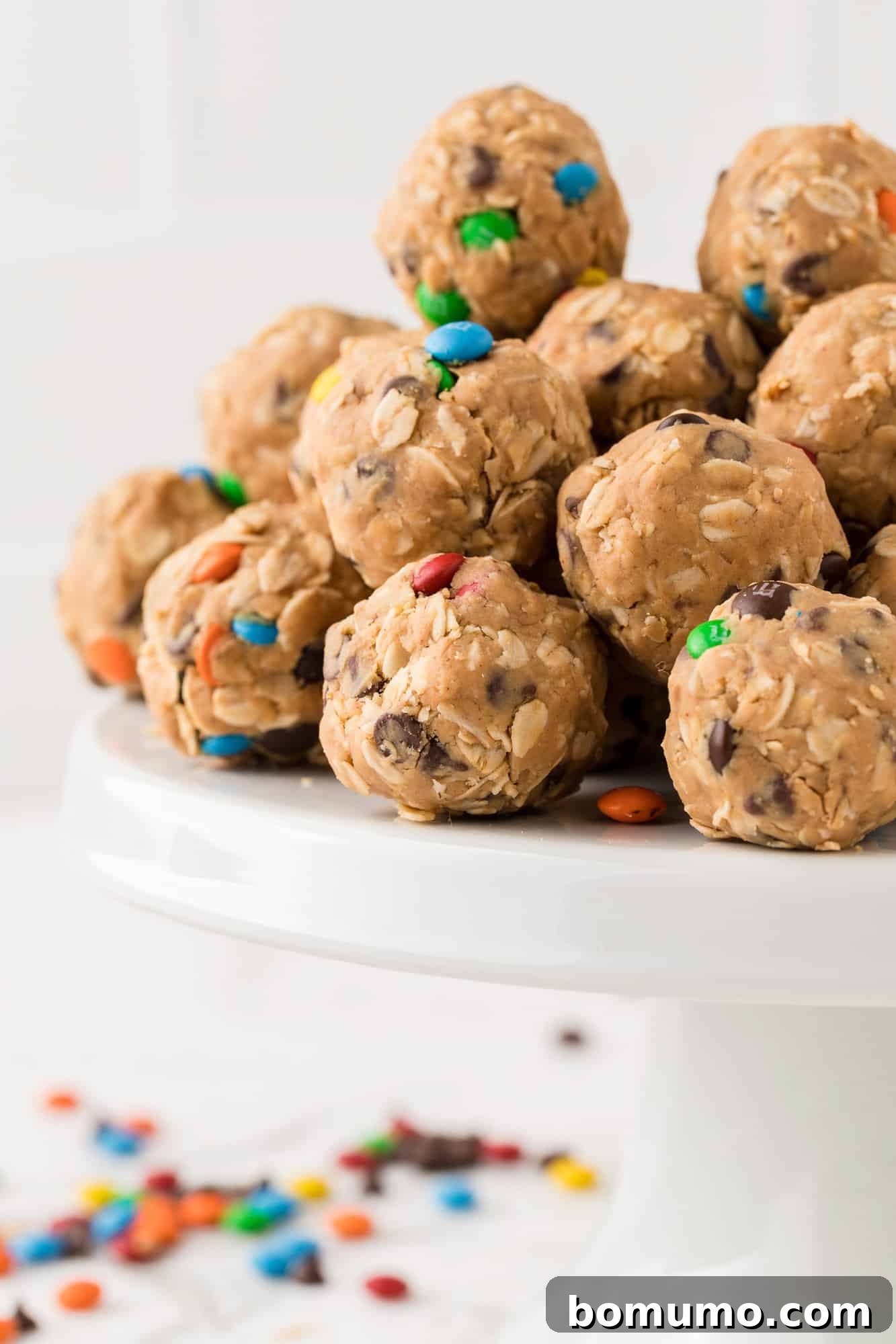 A beautiful display of Monster Cookie Energy Bites artfully piled on a rustic cake stand, ready to be enjoyed as a wholesome snack.