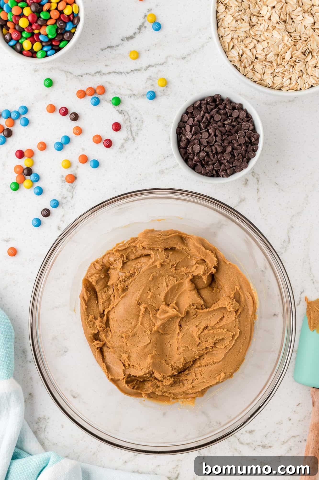 A large mixing bowl containing a smooth, creamy blend of peanut butter, maple syrup, vanilla, and protein powder, ready for the next step of the energy ball recipe.