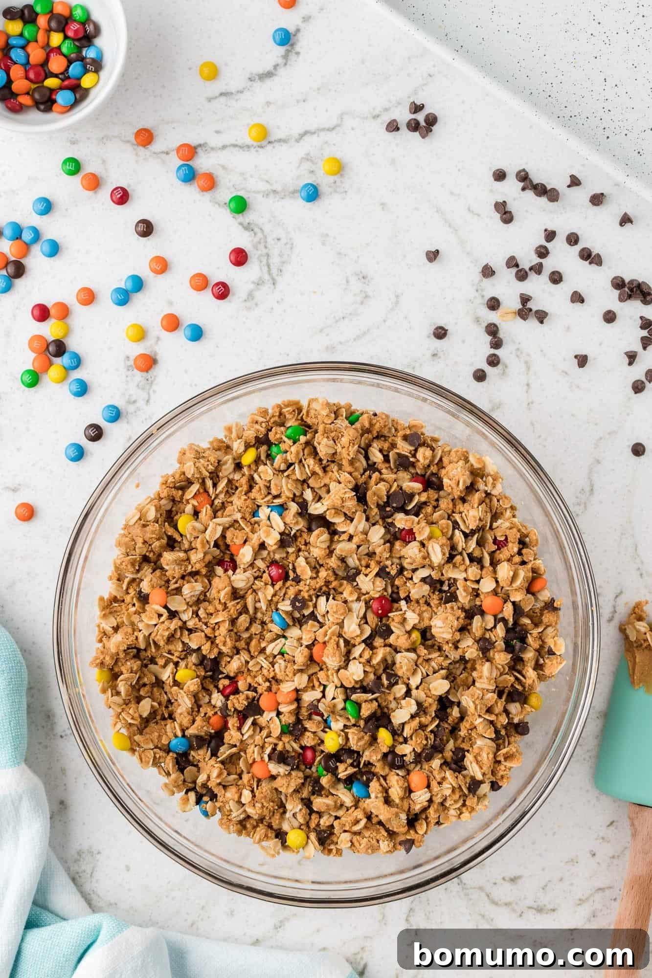 A large mixing bowl filled with the completed monster cookie mixture, studded with vibrant M&M's and chocolate chips, before being rolled into individual energy balls.