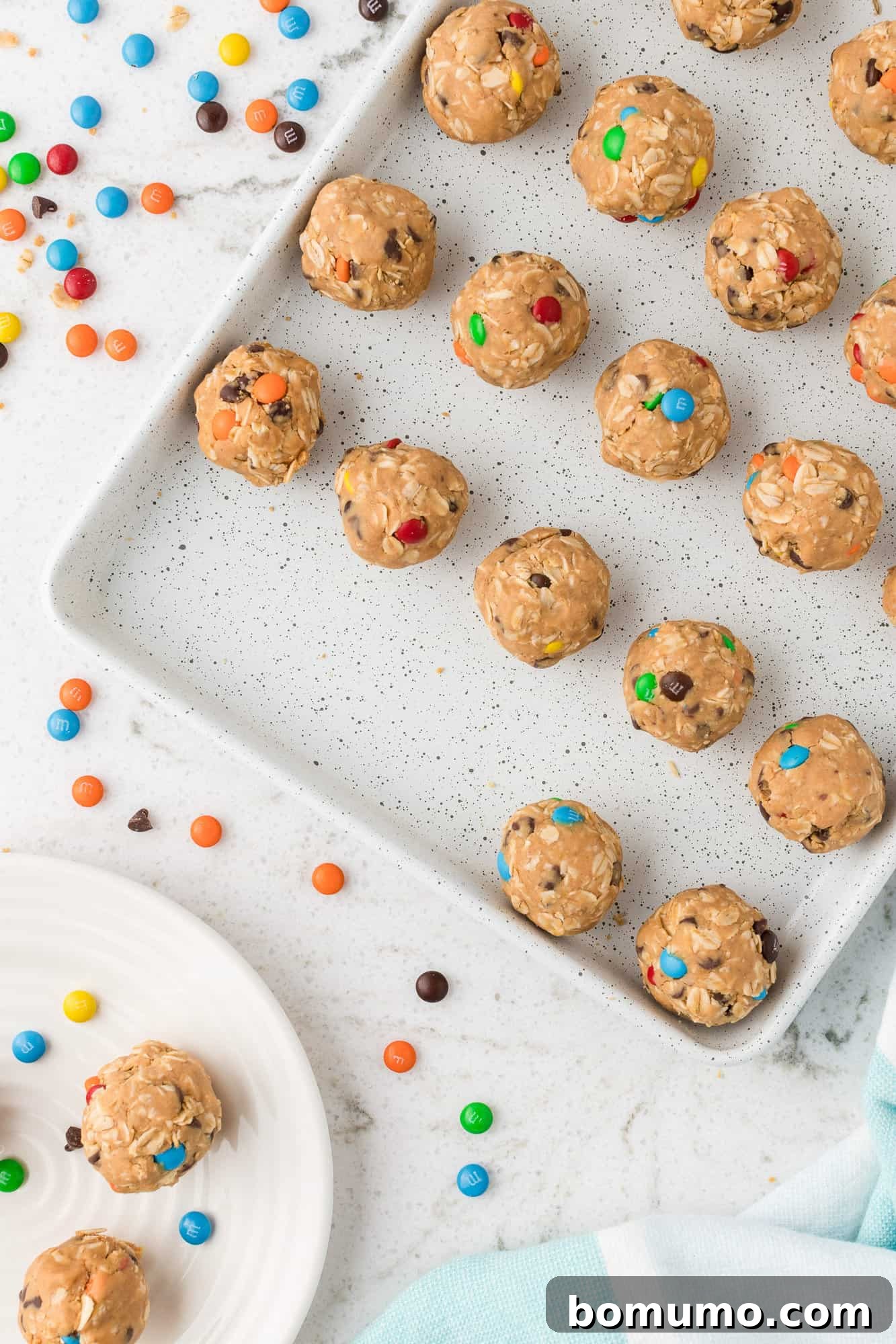 Freshly rolled Monster Cookie Energy Bites, perfectly shaped and arranged on a sheet pan, ready for chilling.