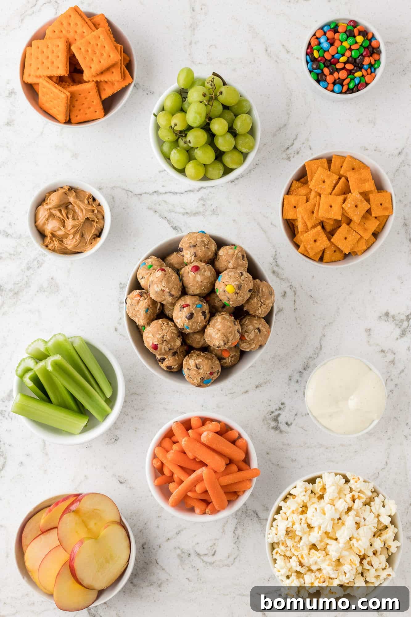 Individual snack components artfully arranged in separate bowls, ready for board assembly.
