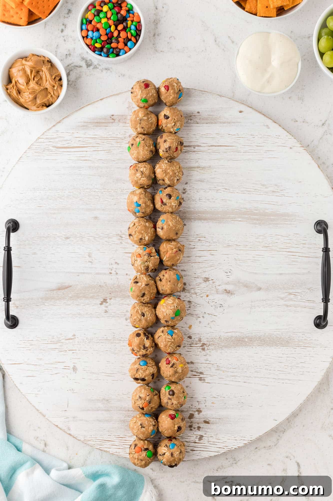 Rows of homemade monster cookie energy bites neatly placed on a snack board.