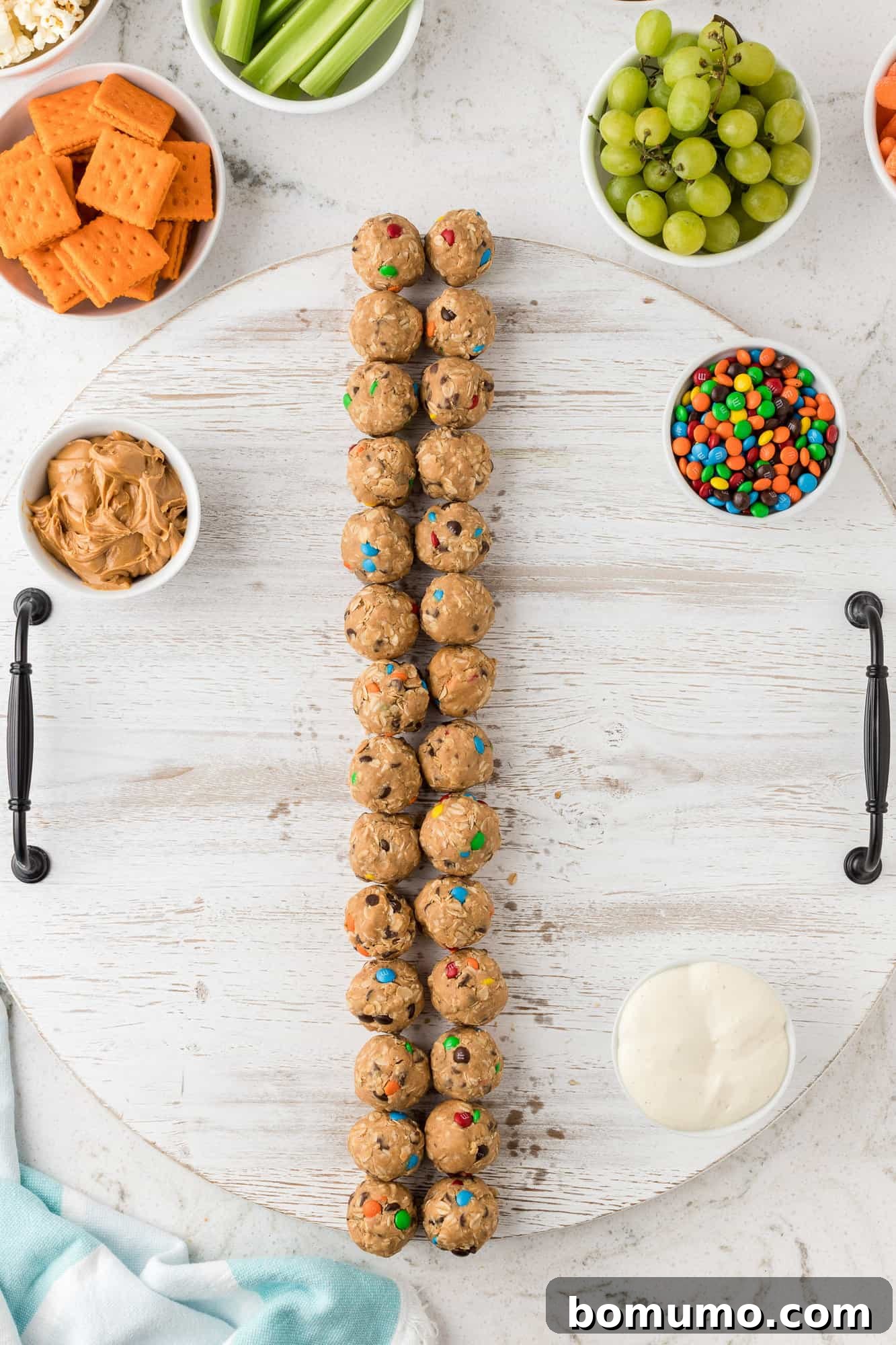 Small bowls containing dips and loose snacks positioned on the edge of a snack board.