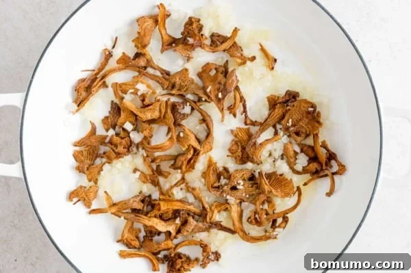 Sautéing Aromatics with Chanterelle Mushrooms Rehydrated chanterelle mushrooms being sautéed in a skillet with fragrant garlic and onions.