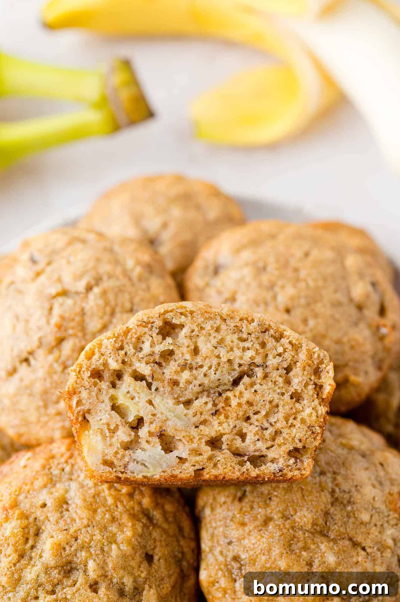 Pile of banana bread muffins, one cut to show texture.