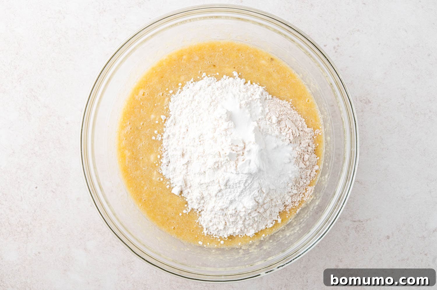 Dry ingredients added to the top of wet ingredients in the same bowl.
