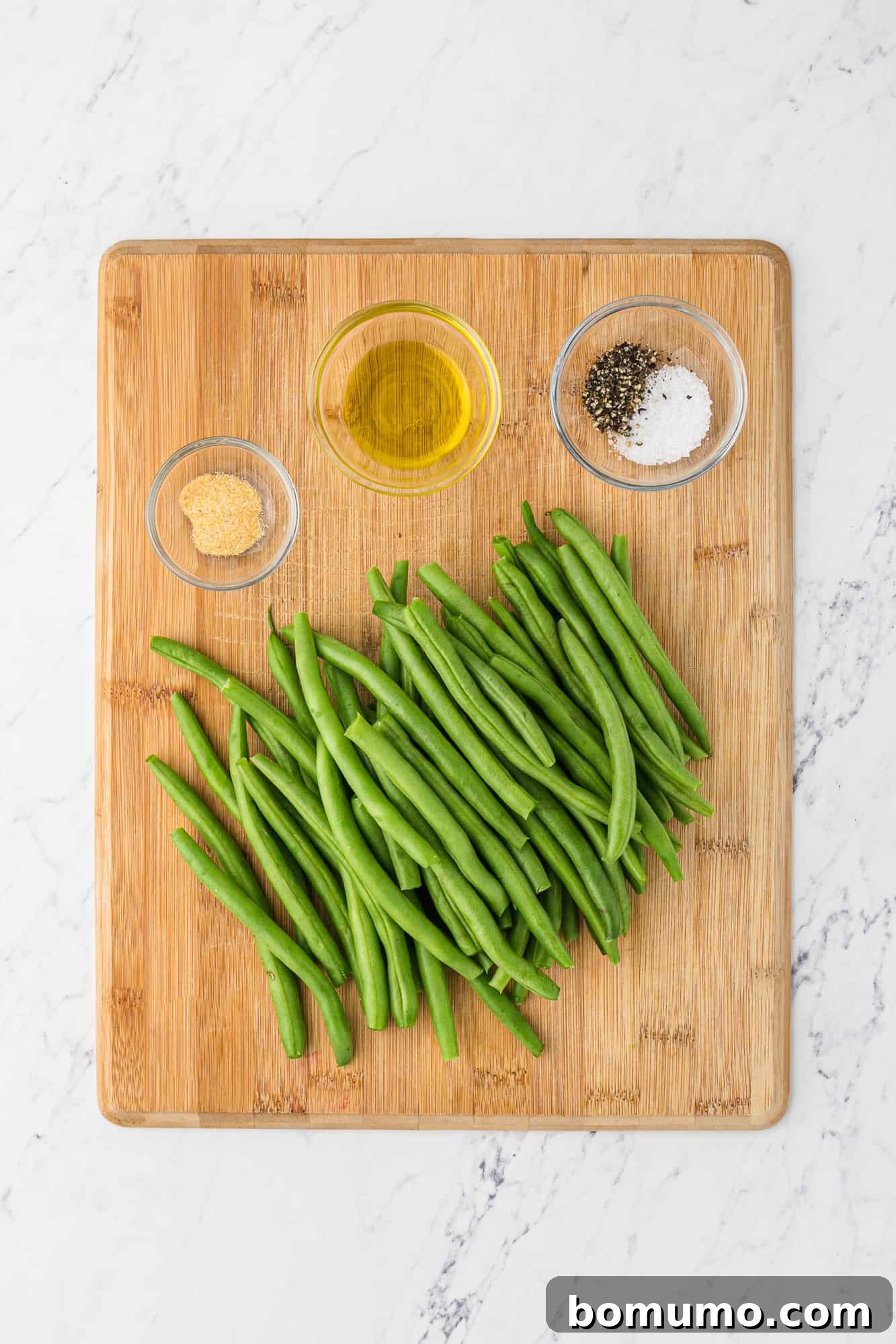 The essential ingredients laid out: fresh green beans and a small bowl of garlic powder, ready for preparation.