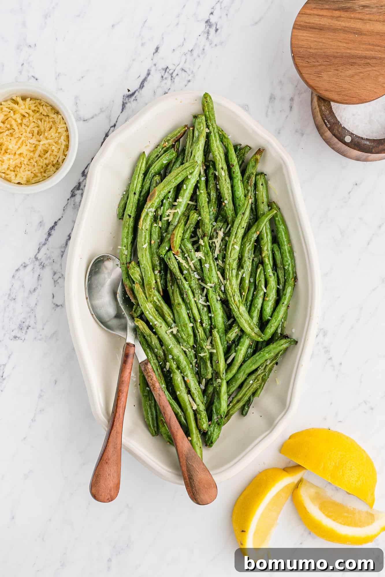 A generous serving of beautifully cooked air fryer green beans on a white platter, ready for the table.