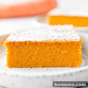 A square image of a baked carrot soufflé, golden brown and lightly puffed, in a baking dish.