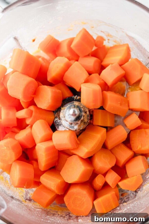 Various carrot soufflé ingredients, including eggs, flour, and spices, are combined in a food processor, illustrating the first stage of blending.
