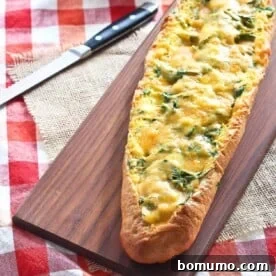 A close-up image showing a golden-brown egg boat, filled with a creamy egg mixture, spinach, and melted cheese, ready for serving.