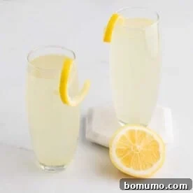 Two French 75 cocktails garnished with elegant lemon twists, set against a chic backdrop.