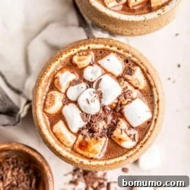 Overhead view of oat milk hot chocolate topped with fluffy marshmallows, served in a rustic mug.