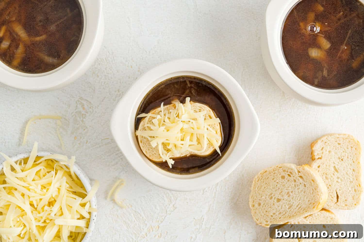 French onion soup in a crock with bread and grated Gruyère cheese, before broiling.