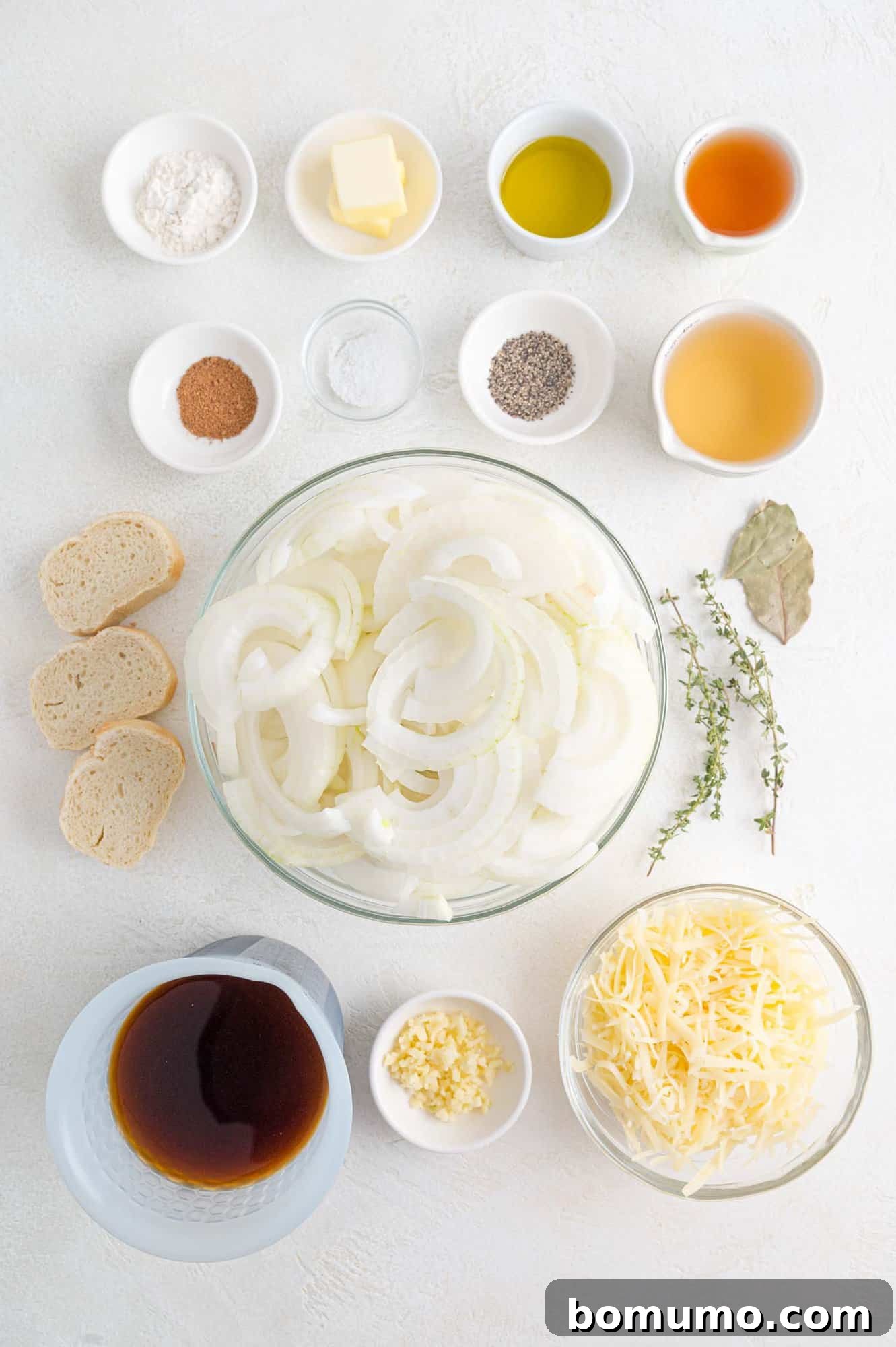 Ingredients for French onion soup, including whole onions, Gruyère cheese, and a baguette.