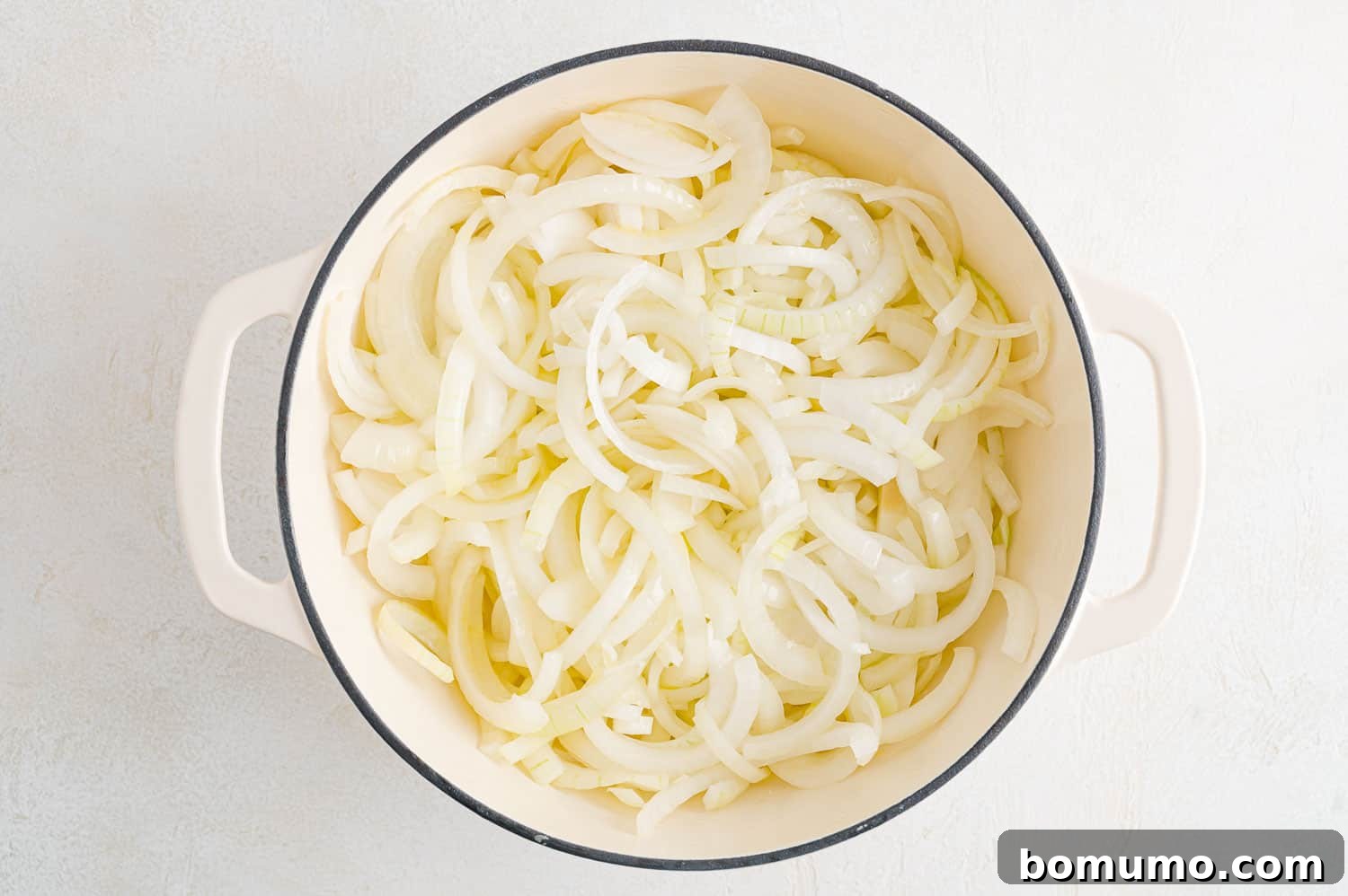 Freshly sliced onions mixed with butter and olive oil in a Dutch oven, before cooking.